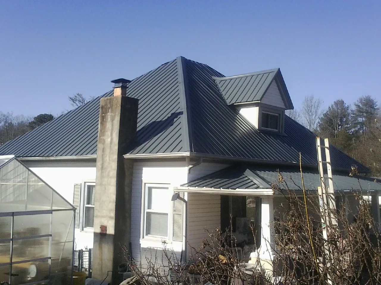 Dark blue standing seam metal roof on a white farmhouse with dormer — Slate & Tile Roof Repair by Roofing Brothers in Pocono Lake