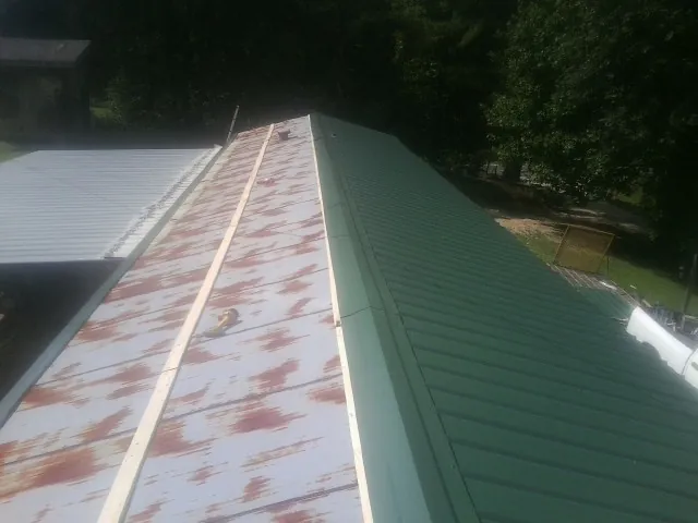 Old rusted panels beside newly installed green metal roofing — Wind Damage Roof Repair by Roofing Brothers in Pocono Lake