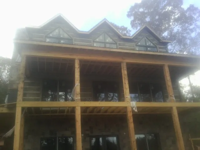 Dormers and porch framing on a large log home under construction — Roof Coating work by our crew in Pocono Lake