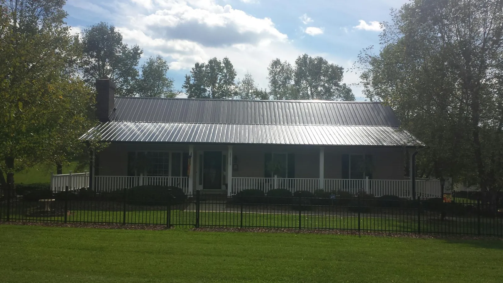 Gray metal roof on a brick ranch with a full width front porch — Gutter Guard Installation work by our crew in Pocono Lake