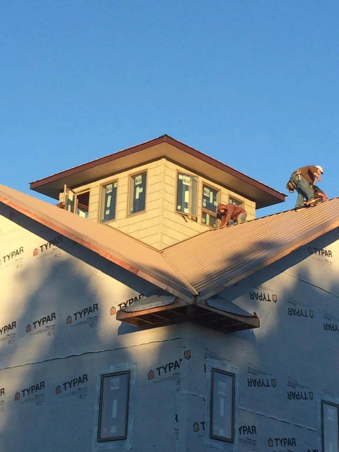Roofers working around a rooftop cupola on a new metal roof at sunset — Roof Waterproofing in Pocono Lake by Roofing Brothers